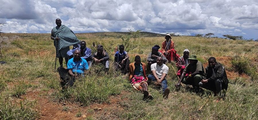 Listening session with Maasai community members in a grass field, Kenya